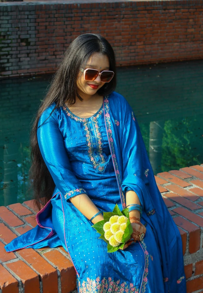 Smiling woman in blue dress holds sweets by water